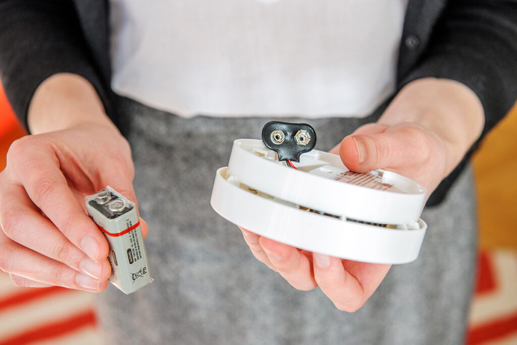 close-up of person changing the battery in a carbon monoxide detector.