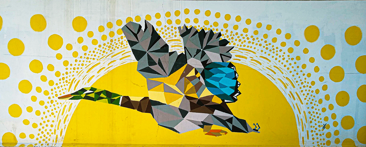 An abstract mural located in Harrison, Arkansas, depicting a colorful duck in flight against a bright yellow sun.